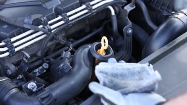 İşçi arabada motor yağı seviyesini dipstick ile kontrol ediyor.