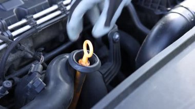 İşçi arabada motor yağı seviyesini dipstick ile kontrol ediyor.