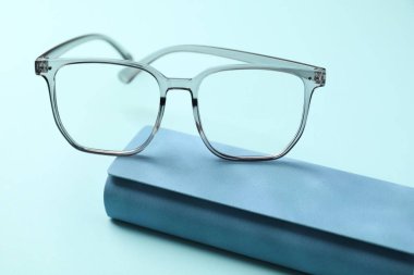 Açık mavi arka planda şık gözlüklü çanta, yakın plan