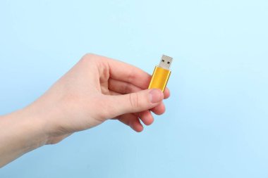 Flaş belleği açık mavi arka planda tutan kadın, yakın plan. Metin için boşluk