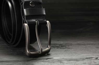 Ahşap masada siyah deri bir kemer, yakın plan. Metin için boşluk