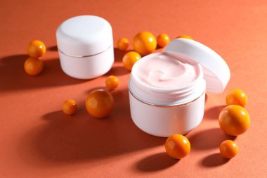 Kavanozlar dolusu nemlendirici vücut kremi ve turuncu arka planda toplar, yakın plan.