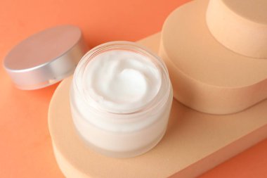 Turuncu arka plandaki kavanozda nemlendirici vücut kremi sunumu, yakın plan.