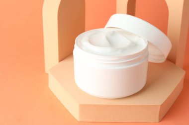 Turuncu arka plandaki kavanozda nemlendirici vücut kremi sunumu, yakın plan. Metin için boşluk