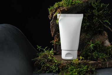 Nemlendirici vücut kremi, ağaç kabuğu ve bitkiler gri masada, yakın plan. Metin için boşluk