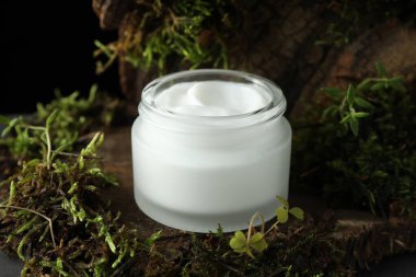 Ağaç kabuğunda bitkilerle birlikte nemlendirici vücut kremi, yakın plan.