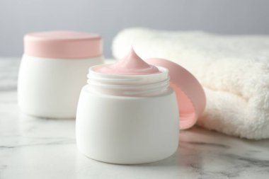 Beyaz mermer masanın üzerinde bir kavanoz nemlendirici vücut kremi, yakın plan.