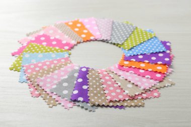 Beyaz ahşap masadaki farklı kumaşlardan örnekler, yakın plan.