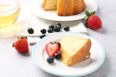 Açık gri masada böğürtlenli kek ve çay, yakın plan.