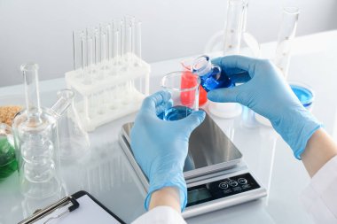 Laboratuvardaki beyaz ayna masasında numune ve terazilerle çalışan bilim adamı.