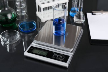 Siyah ayna masasındaki deney tüpü ve diğer laboratuvar camlarıyla ölçeklendir, yakın plan.