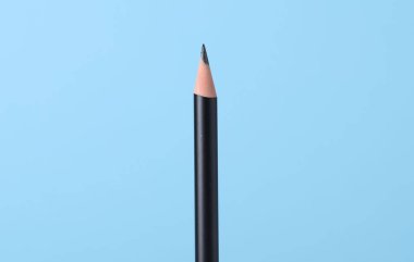 Açık mavi arkaplanda keskin grafit kalem, yakın plan