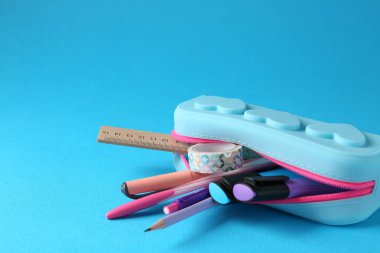 Açık mavi arka planda, kalem kutusunda farklı bir kırtasiye malzemesi, yakın plan. Metin için boşluk