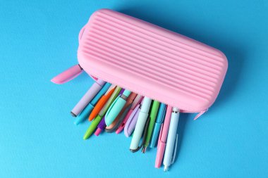 Açık mavi arkaplan üzerindeki kalemler ve kalemler, üst görünüm