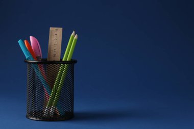 Koyu mavi arka planda kalem tutacağında farklı bir kırtasiye malzemesi. Metin için boşluk