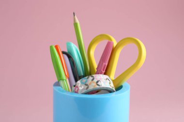 Pembe arka planda kalem tutacağında farklı bir kırtasiye, yakın plan