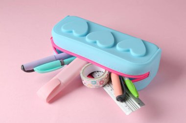 Pembe arka planda kalem kutusunda farklı bir kırtasiye, yakın plan