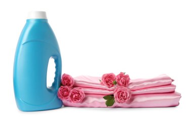 Bir şişe yumuşatıcı, üst üste yığılmış giysiler ve beyaza saklanmış çiçekler.