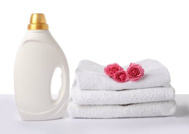 Bir şişe yumuşatıcı, beyaz üzerine izole edilmiş havlular ve çiçekler.