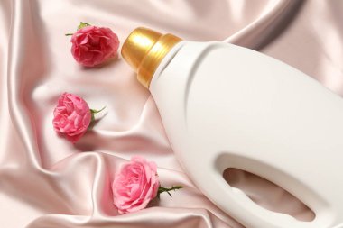 Bir şişe yumuşatıcı ve bej kumaşlı çiçekler.