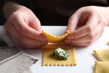 Beyaz masada peynirli ve ıspanaklı ravioli yapan kadın, yakın plan.