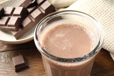 Bardakta çikolatalı süt ve ahşap masada malzeme, yakın plan.