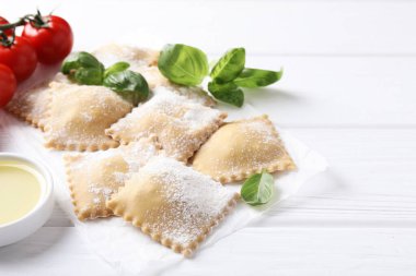 Pişmemiş ravioli, fesleğen, domates ve yağ beyaz ahşap masada, yakın plan.
