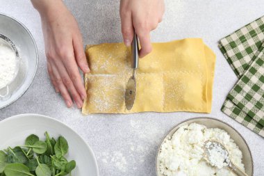 Işık masasında ravioli kesen kadın, üst manzara.