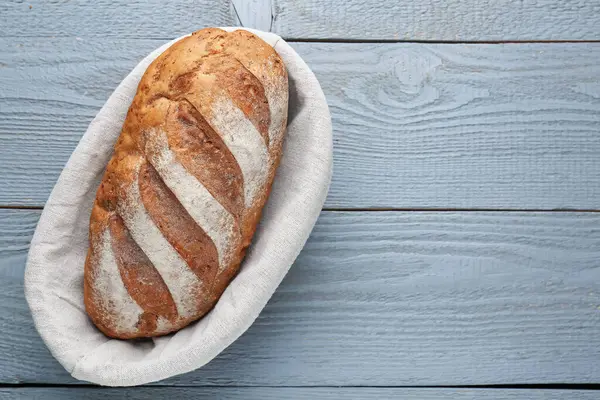 Gri ahşap masada, sepetin içinde bir somun ekmek, üst manzara. Metin için boşluk