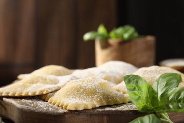 Ahşap masada pişmemiş ravioli ve fesleğen, yakın plan. Metin için boşluk
