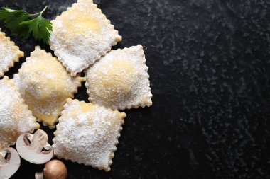 Pişmemiş ravioli, maydanoz ve mantarlar siyah masada, düz yerde. Metin için boşluk