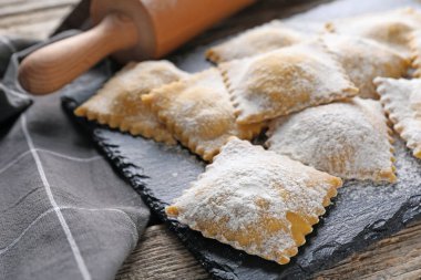 Pişmemiş ravioli ve merdane ahşap masada, yakın plan.