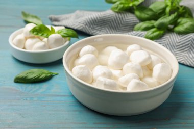 Mozzarella peynir topları ve fesleğen mavi ahşap masada, yakın plan.