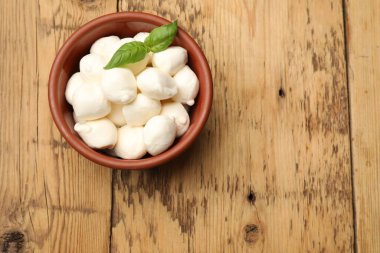 Mozzarella peyniri topları ve fesleğen, ahşap masa, üst manzara. Metin için boşluk