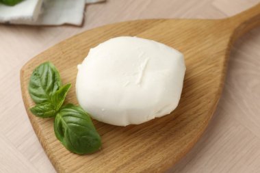 Ahşap masada mozzarella peyniri ve fesleğen, yakın plan.