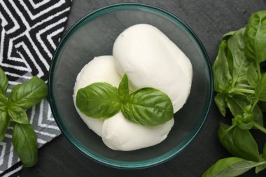 Lezzetli mozzarella peyniri ve fesleğen parçaları koyu dokulu masada, düz yerde.
