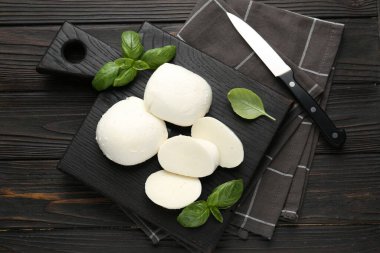 Lezzetli mozzarella peyniri ve fesleğen parçaları ahşap masada, düz yatıyordu.