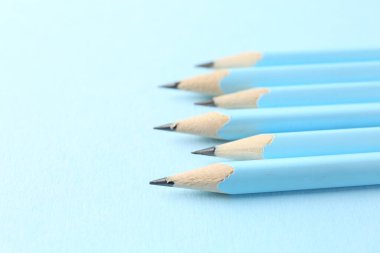 Açık mavi arka planda çizgili kalemler, yakın plan. Metin için boşluk