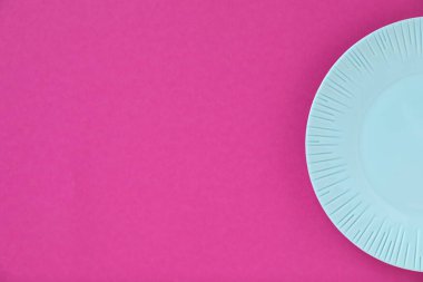 Pembe arka planda boş bir tabak, üst manzara. Metin için boşluk