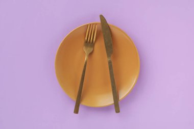 Menekşe arkaplanda boş tabak ve çatal bıçak takımı, üst görünüm