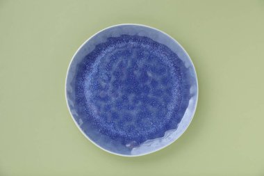 Açık yeşil zemin üzerinde boş bir tabak, üst görünüm