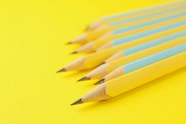 Many graphite pencils on yellow background, closeup. Space for text
