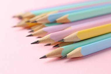 Many graphite pencils on pink background, closeup