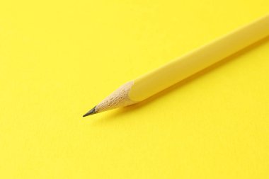 Sarı arkaplanda bir grafit kalem, yakın plan.