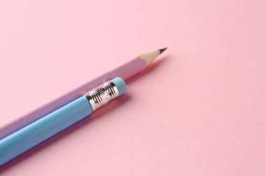 Pembe arka planda iki grafit kalem, yakın plan. Metin için boşluk