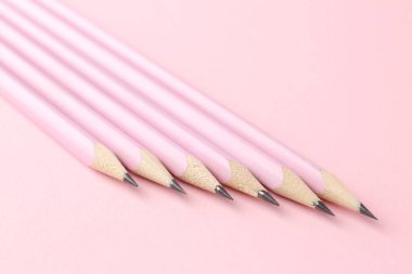Many graphite pencils on pink background, closeup