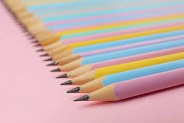 Many graphite pencils on pink background, closeup