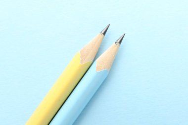 Açık mavi arka planda iki grafit kalem, düz.