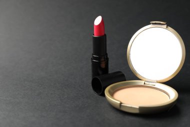 Aynalı açık yüz pudrası ve siyah arka planda ruj, yakın plan. Metin için boşluk