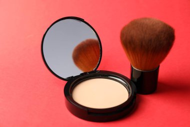 Aynalı yüz pudrasını aç ve kırmızı arkaplanda fırçala, kapat
